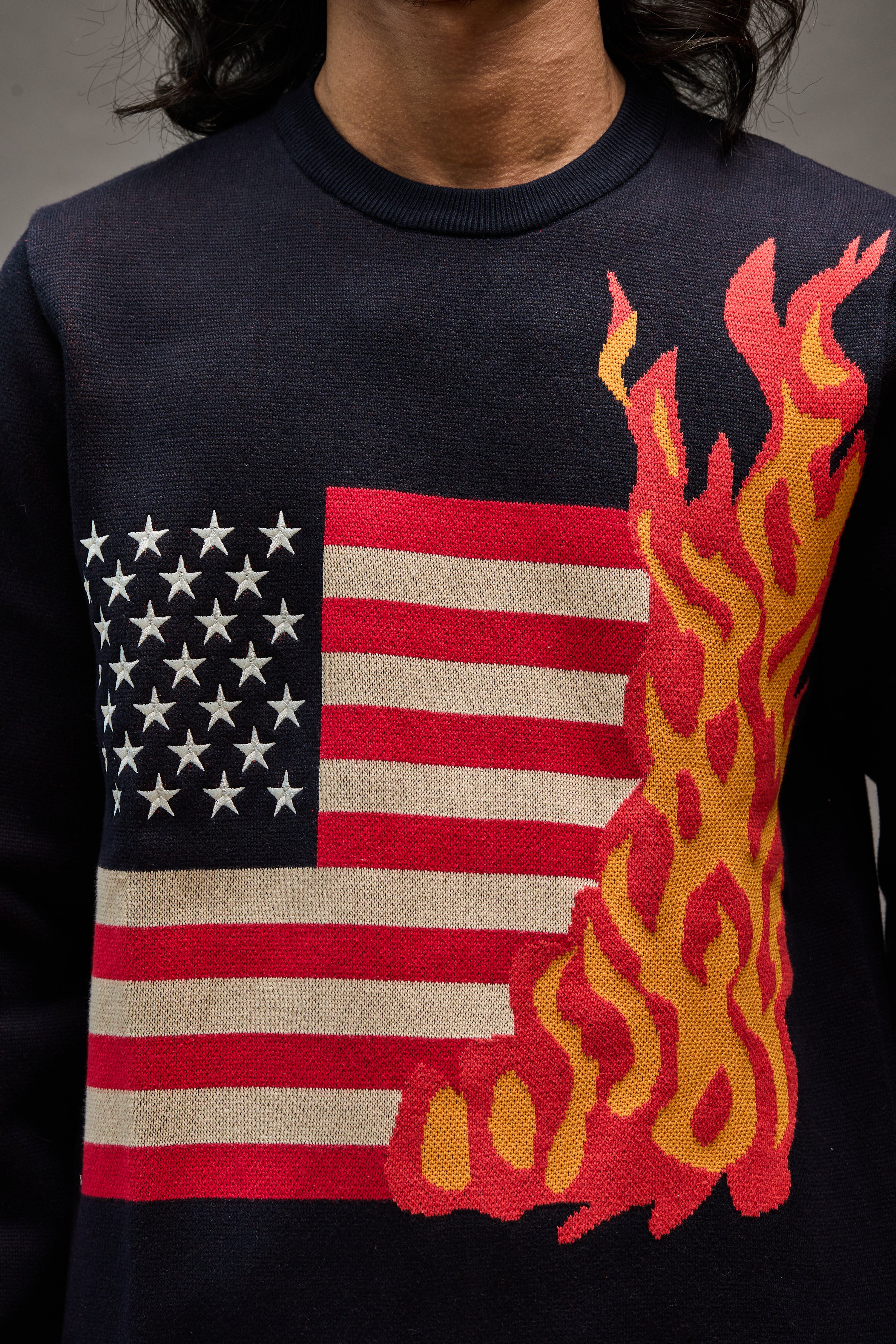 “Close-up of burning American flag design on navy blue 1A Sparks sweater”