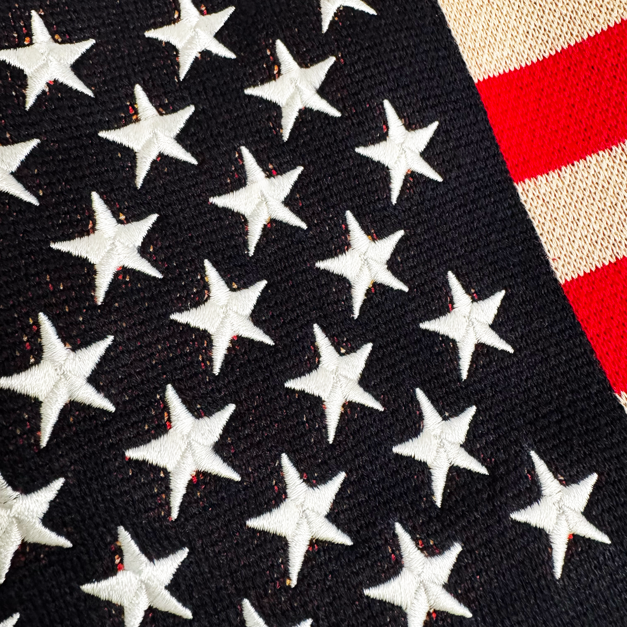 “Detail of embroidered stars and knit texture on navy blue 1A Sparks sweater”