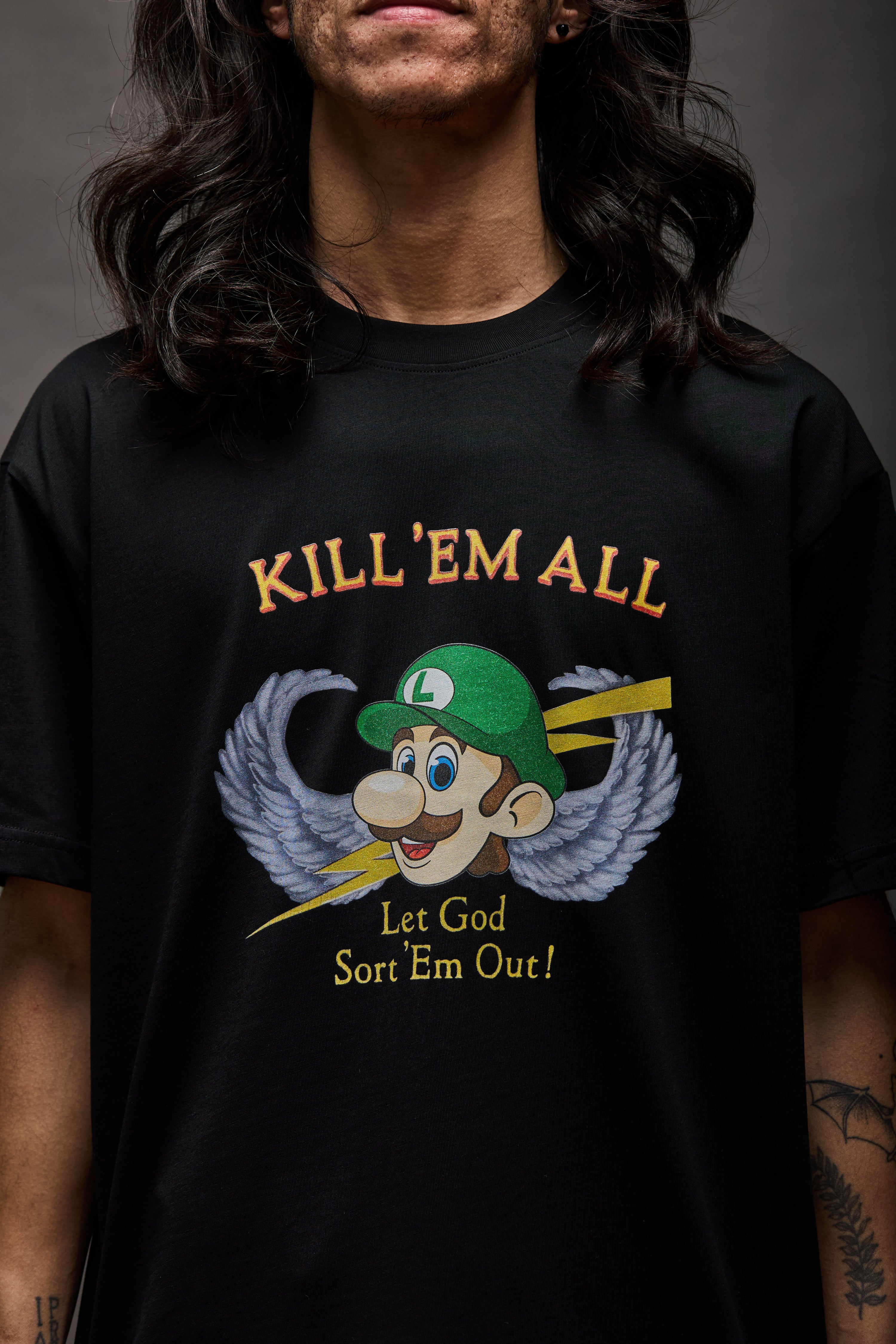 Black T-shirt with “KILL ’EM ALL” in yellow serif text above a winged cartoon character head with lightning bolts; below reads “Let God Sort ’Em Out!”