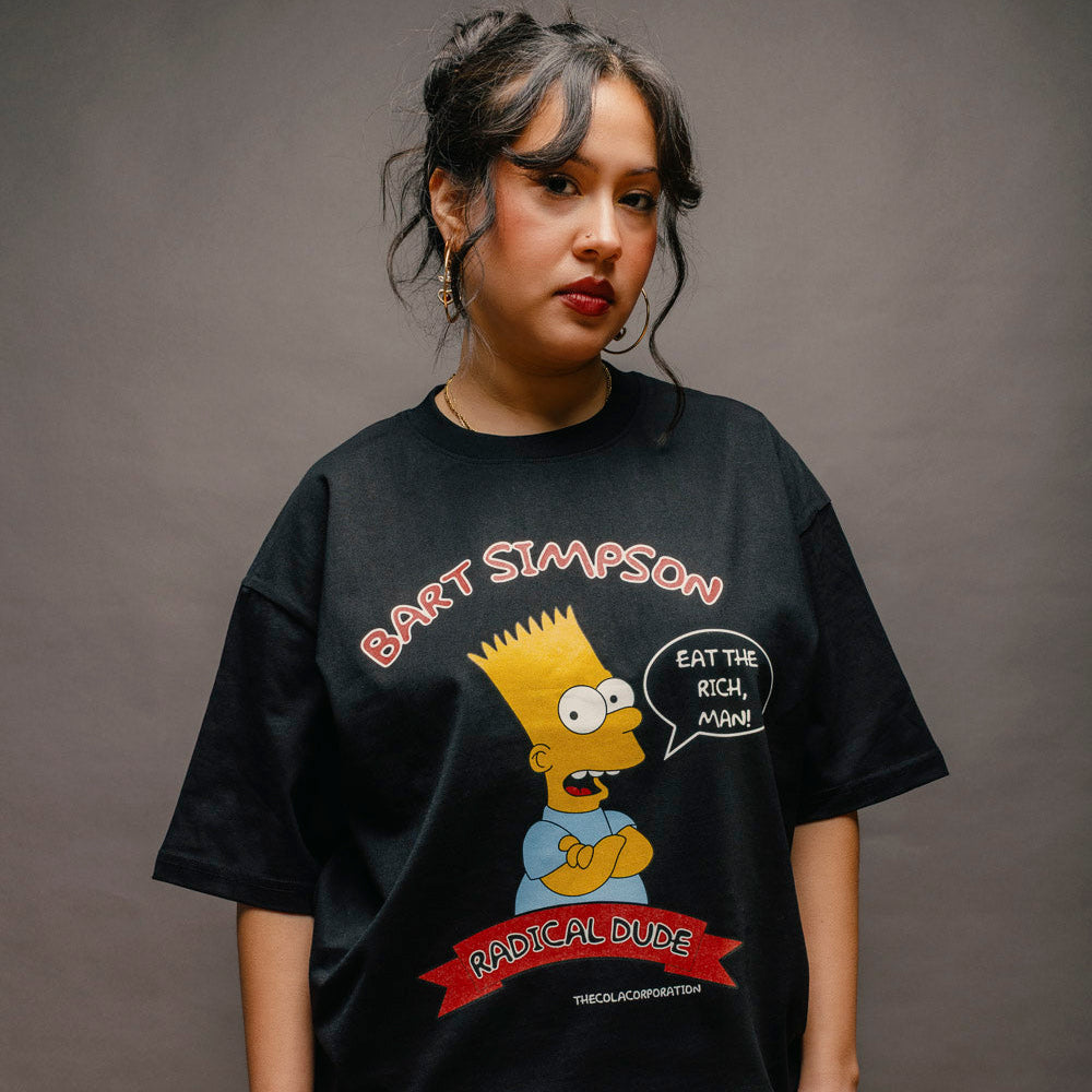 A model wearing a black graphic t-shirt featuring Bart Simpson with the text 'BART SIMPSON' and 'MADNESS DURE' on a dark gray studio background.